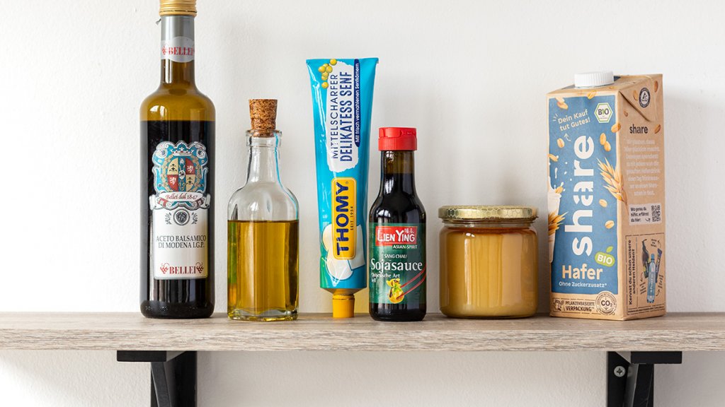 Pflanzenmilch, Honig, Sojasauce, Senf, &Ouml;l und Essig auf einem Regal