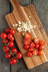 halbierte Tomaten und fein gew&uuml;rfelter Knoblauch auf einem Schneidebrett