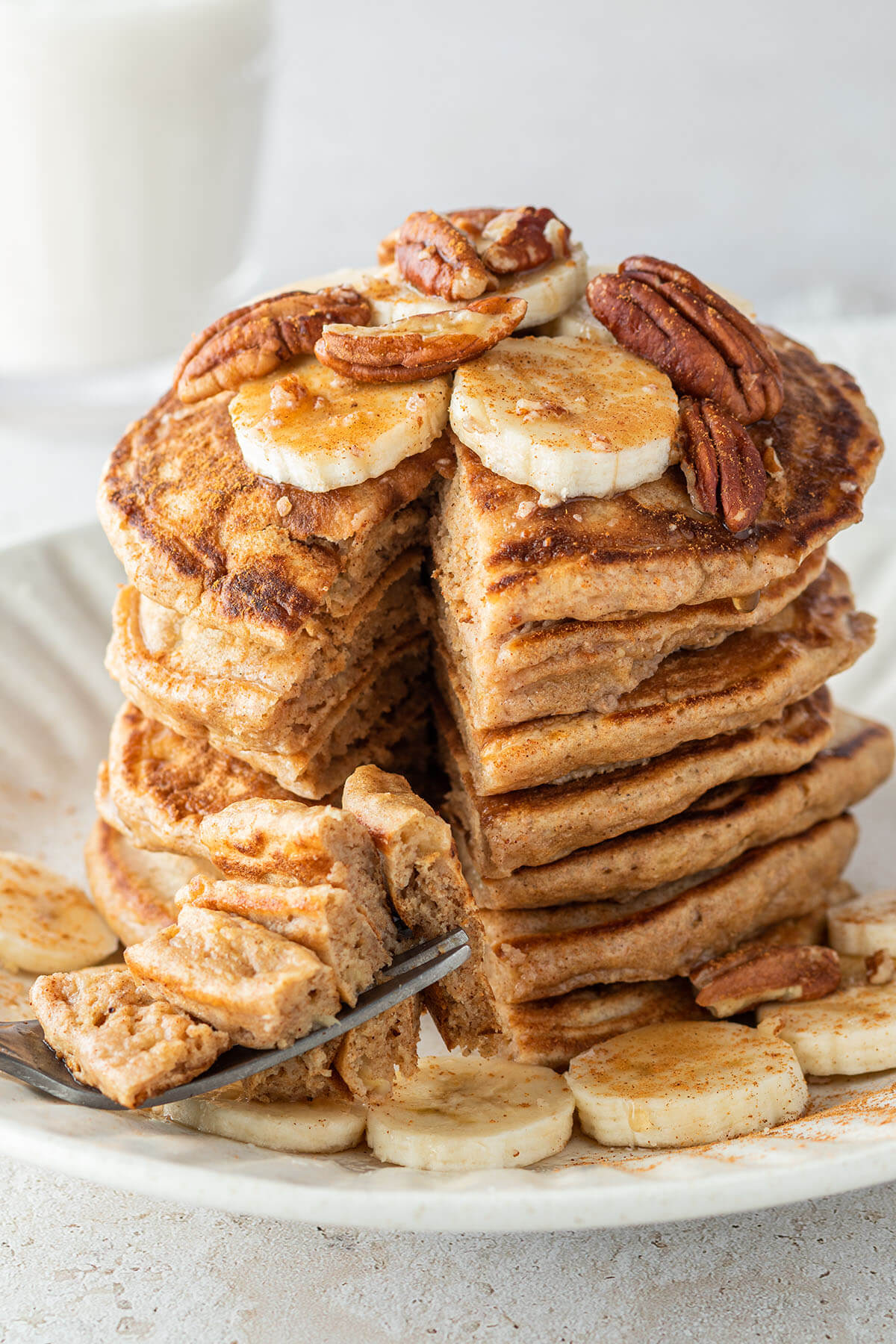 Nahaufnahme von einem angeschnittenen Stapel Pancakes mit frischen Bananen und N&uuml;ssen.