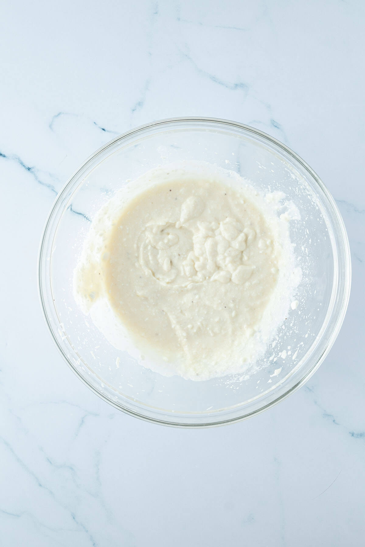 P&uuml;ree aus H&uuml;ttenk&auml;se und Banane in einer gro&szlig;en Glassch&uuml;ssel.