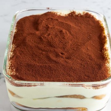 Mit Kakao bestreute Tiramisu ohne Mascarpone und Sahne in einer Glas-Form.