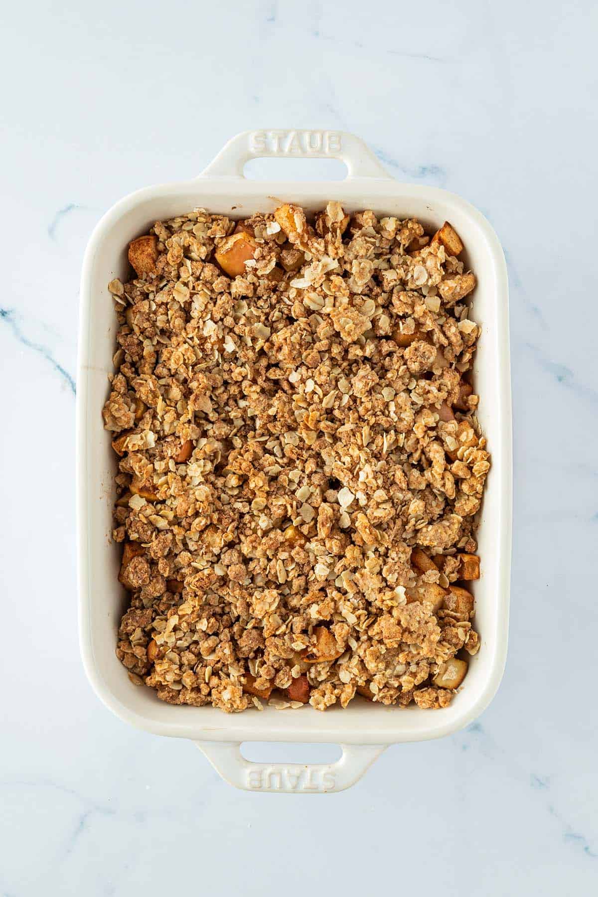 Vogelperspektive auf eine Auflaufform mit Apfel Crumble und knusprig gebackenen Haferflocken-Streuseln.