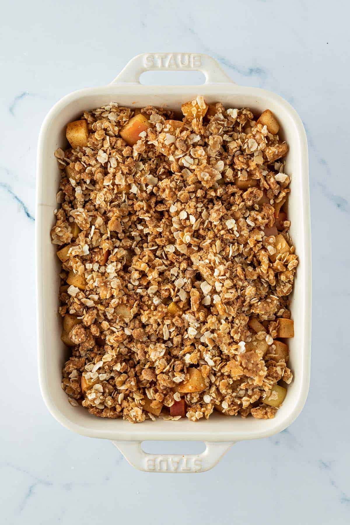 Apfel Crumble mit Haferflocken vor dem Backen im Ofen in einer Auflaufform.