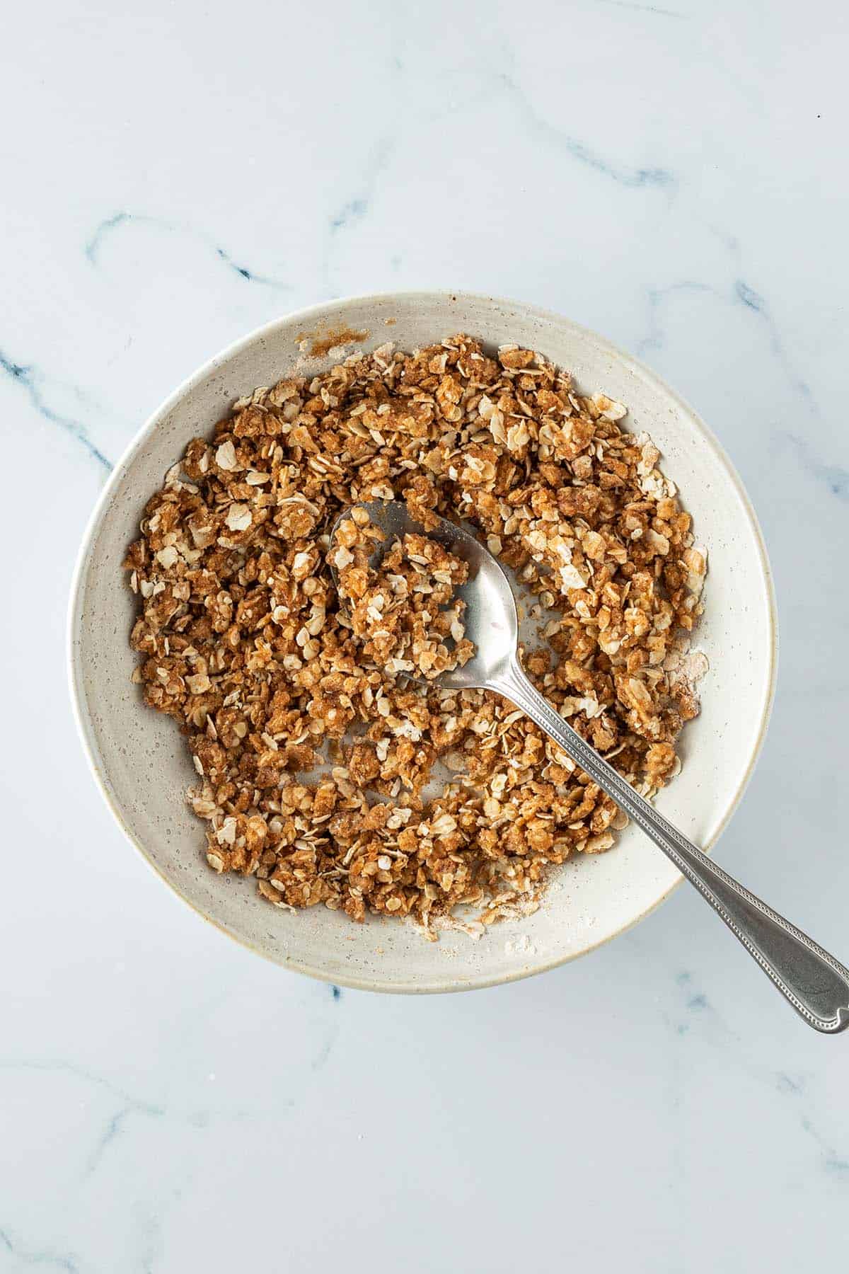 Haferflocken-Streusel mit einem L&ouml;ffel in einer Sch&uuml;ssel.