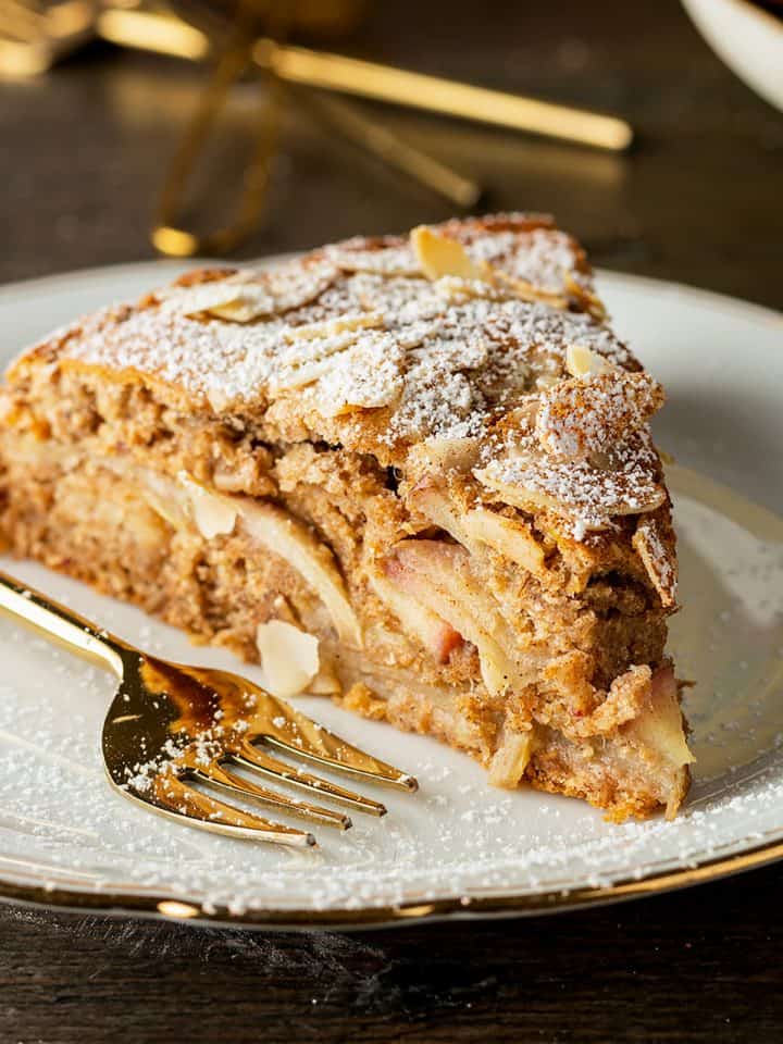 Ein Stück gesunder Apfelkuchen ohne Zucker auf einem weißen Teller mit Kuchengabel.