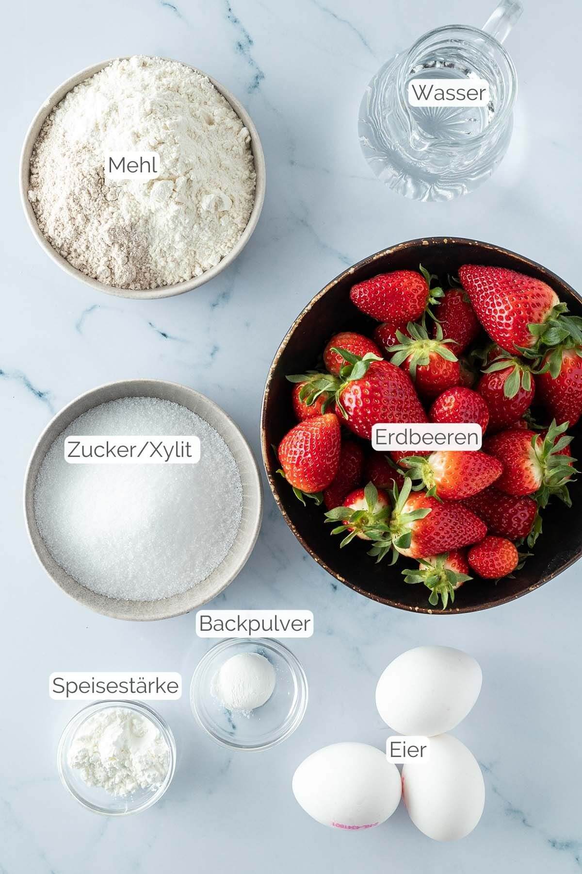 Foto aller Zutaten mit jeweiligen Textbeschriftungen, die f&uuml;r den gesunden Erdbeerkuchen ben&ouml;tigt werden.