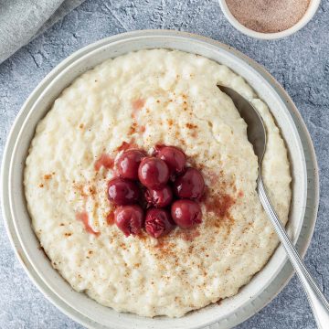 Cremiger Milchreis serviert mit Krischen und Zimt.