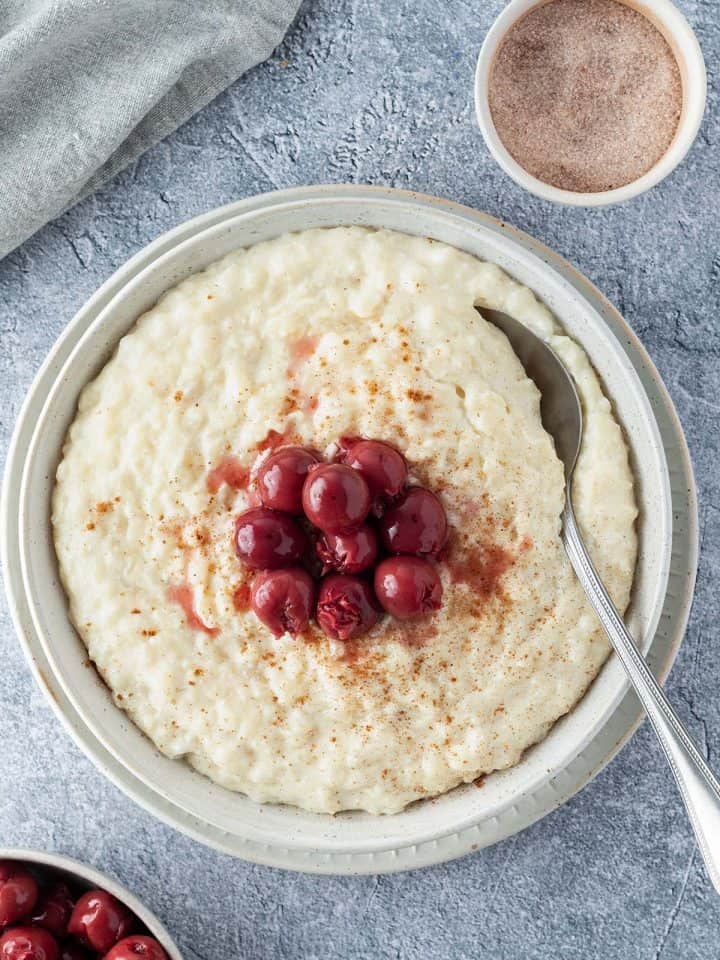 Cremiger Milchreis serviert mit Krischen und Zimt.