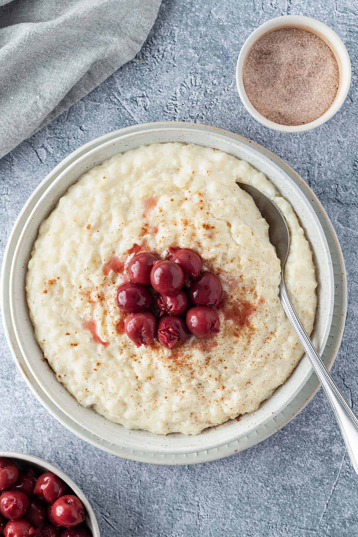 Cremiger Milchreis serviert mit Krischen und Zimt.