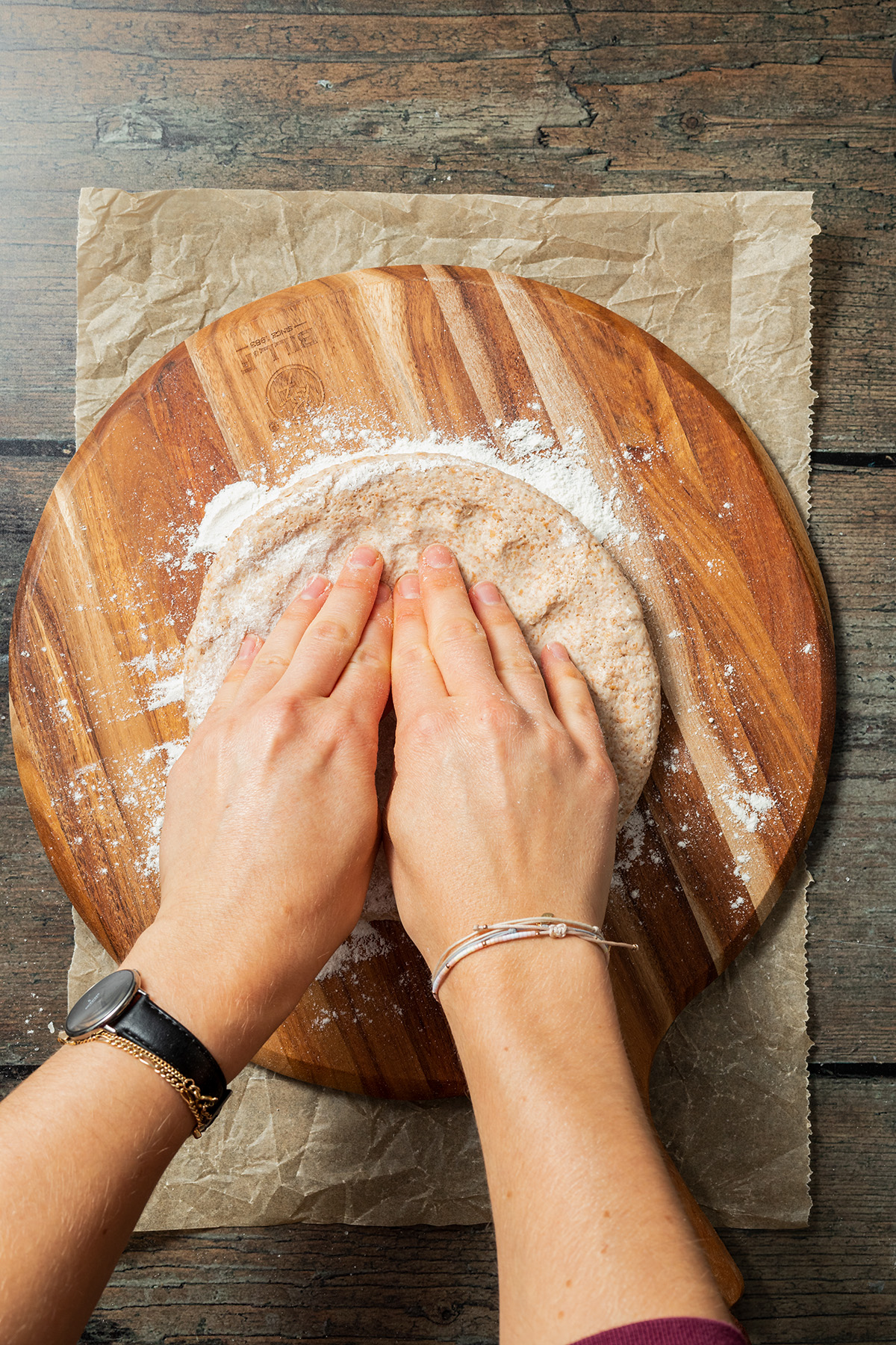 Pizzateig formen: Pizzateig wird mit den Fingern von der Mitte aus an den Rand gedrückt.