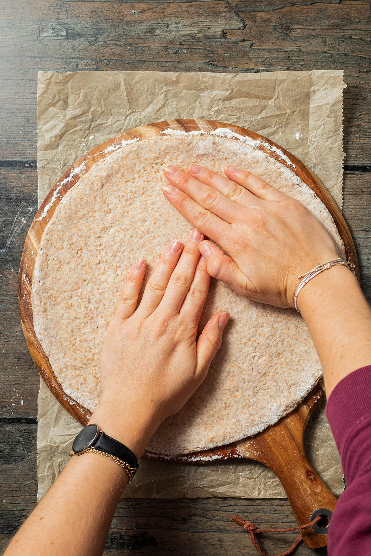 Pizzateig mit den Handflächen zu einer runden Pizza formen.