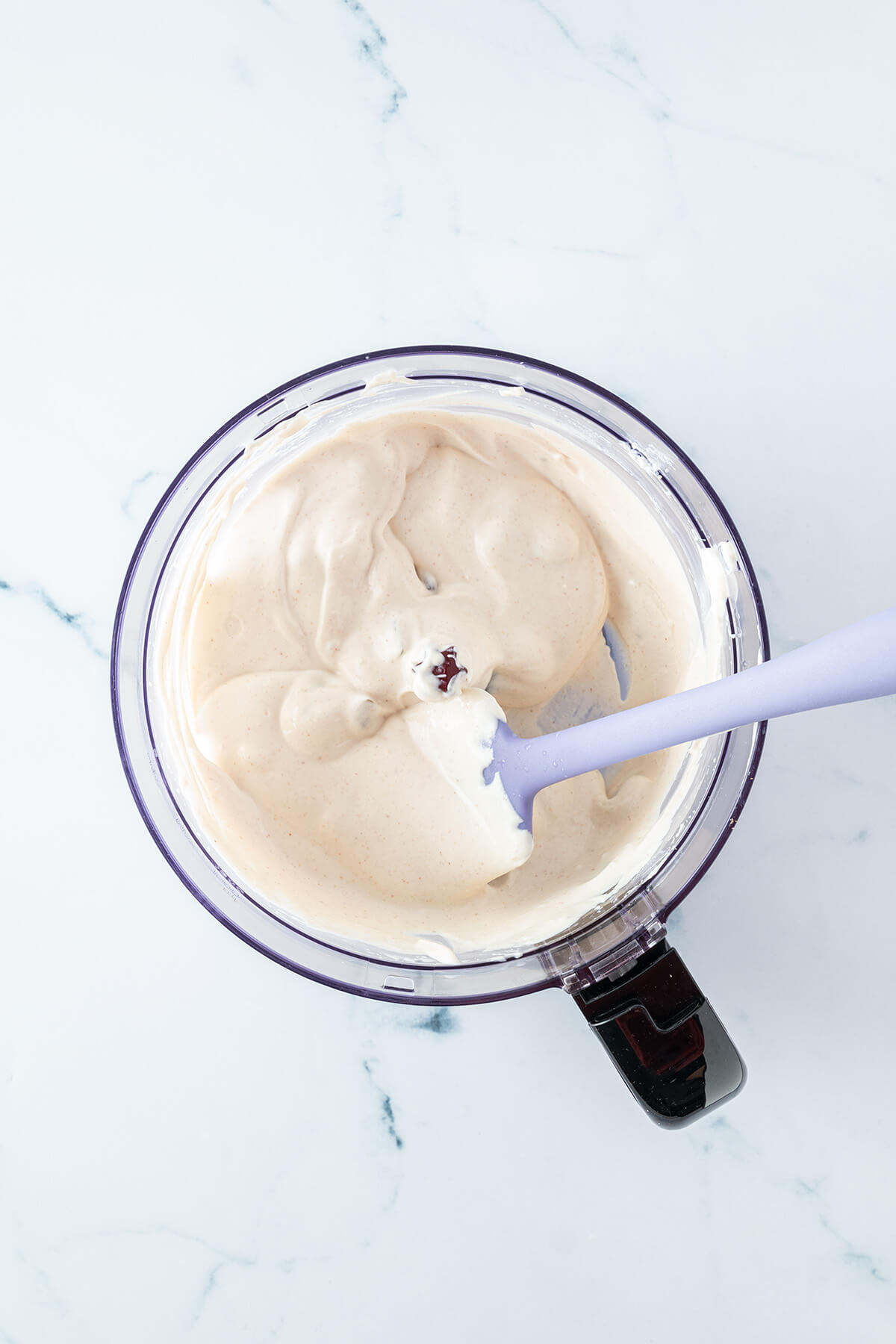 H&uuml;ttenk&auml;se-Creme mit einem Teigschaber in einem Mixer.