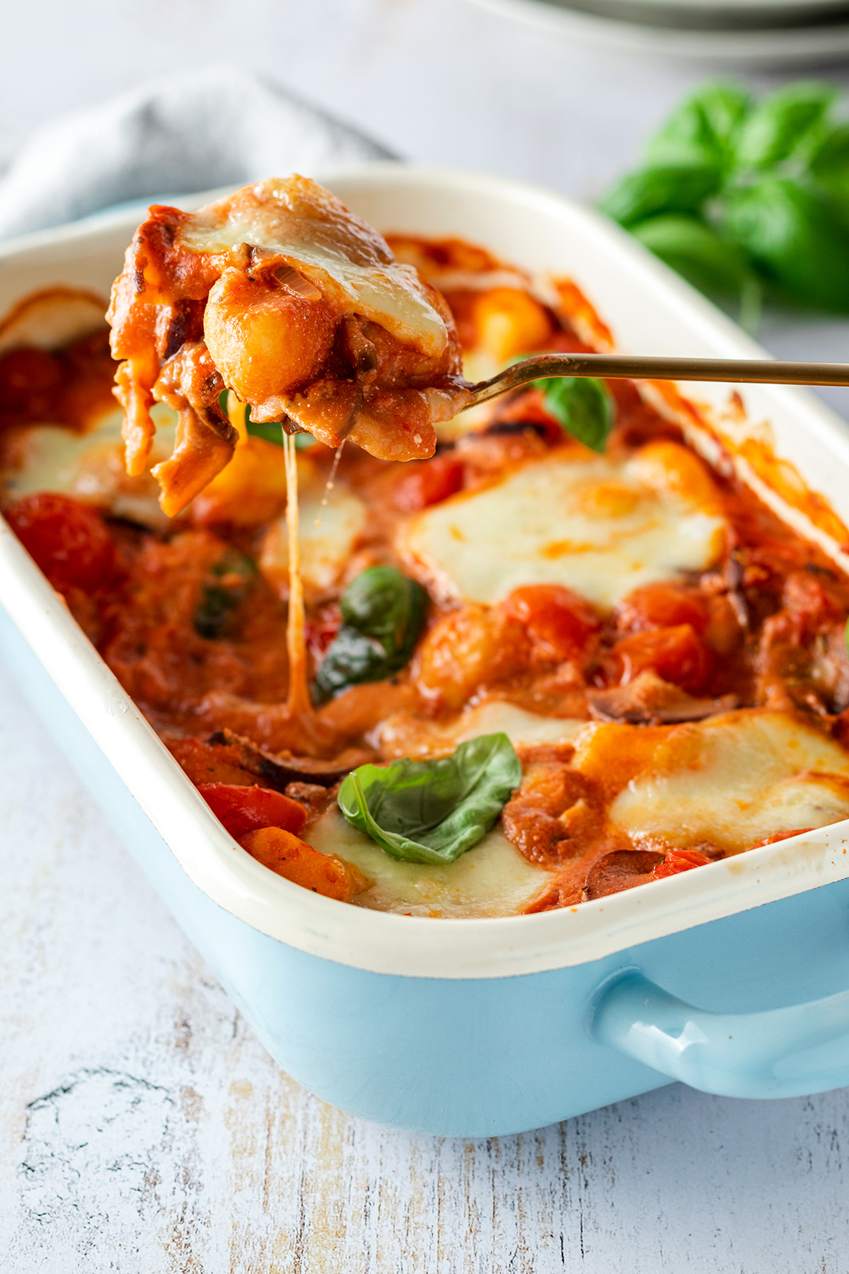 Ein vegetarischer Gnocchi Auflauf mit Tomate Mozzarella und frischem Basilikum serviert in einer Auflaufform.