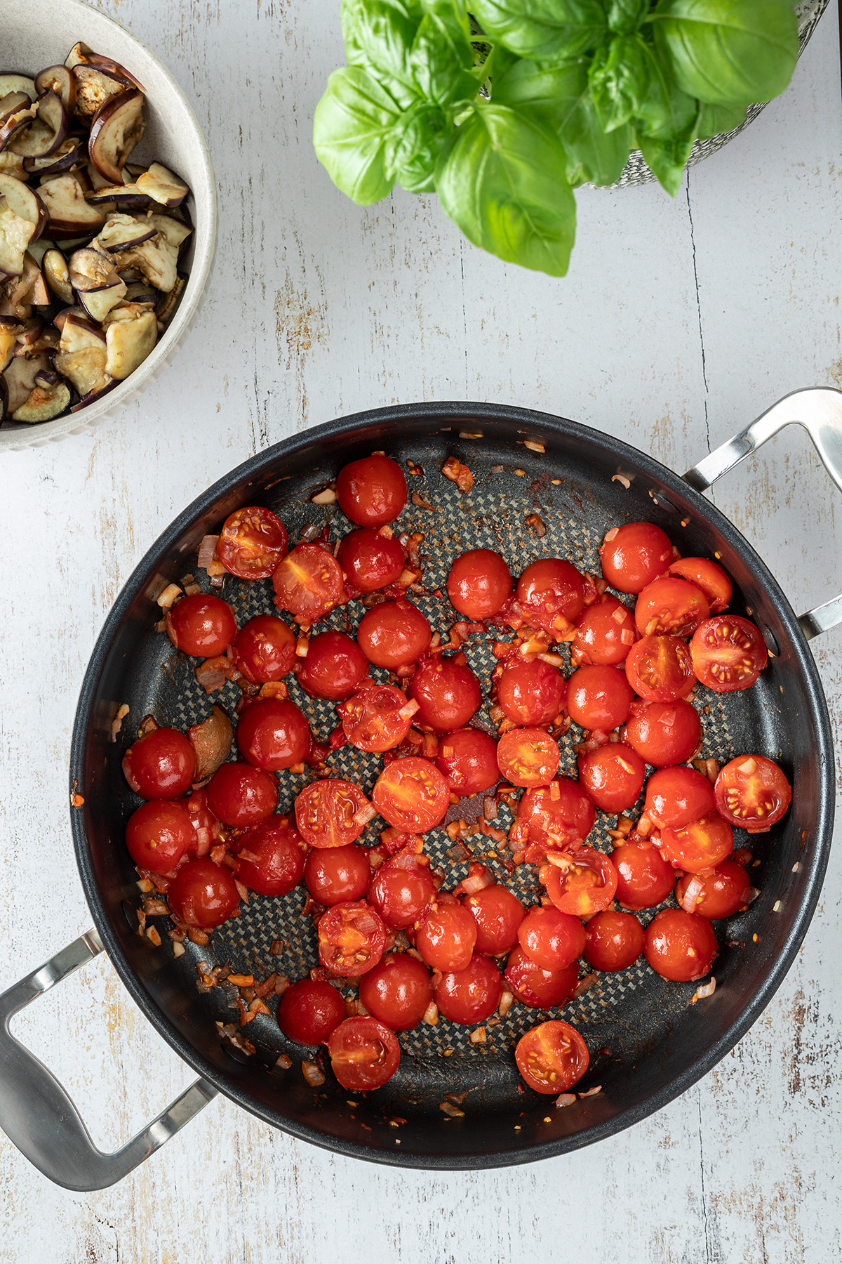 Cherry Tomaten, Zwiebel und Knoblauchw&uuml;rfel in einer gro&szlig;en Pfanne.