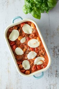 Gnocchi in einer Tomatensauce in einer Auflaufform mit Mozzarella Scheiben oben drauf.