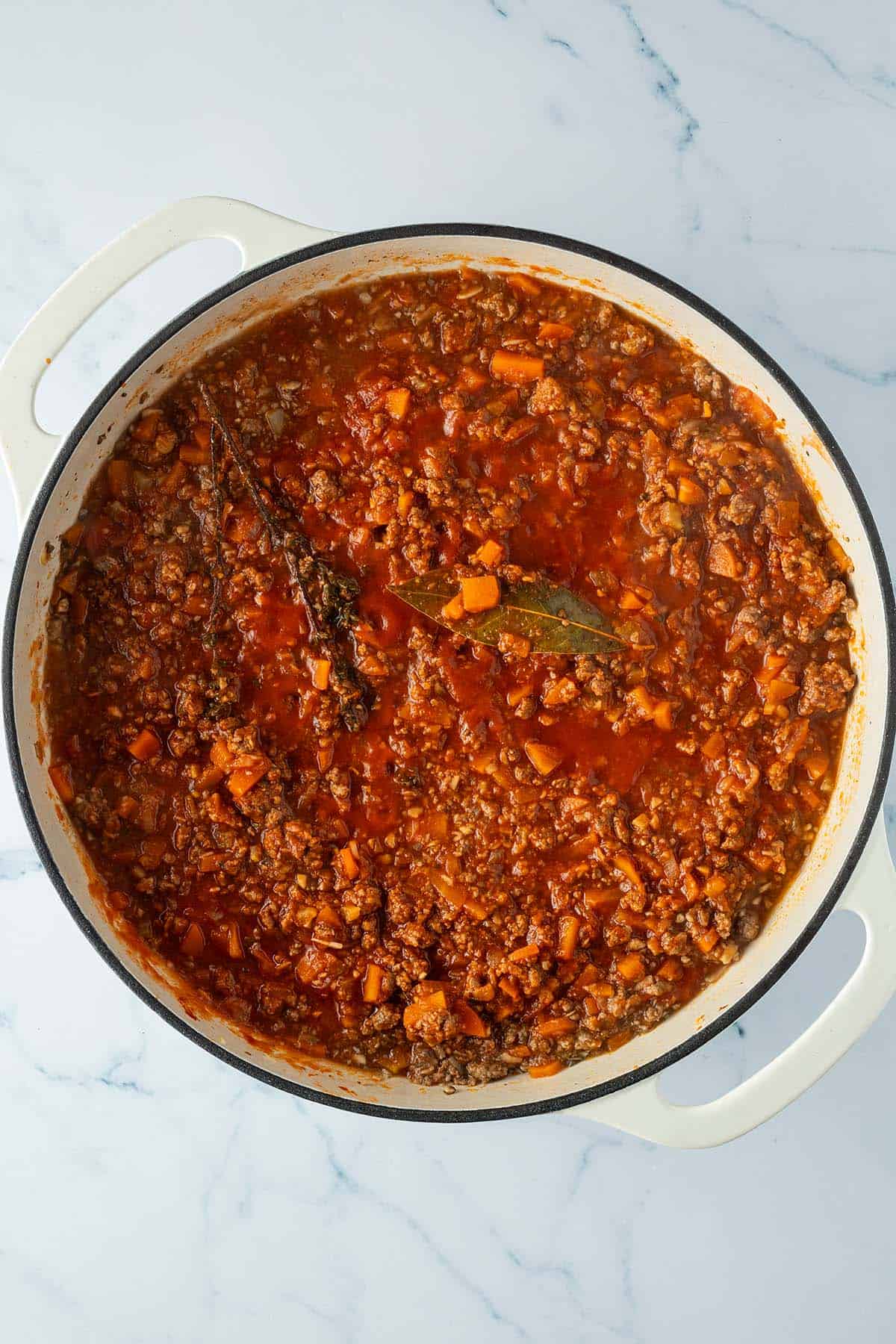 Fertige Hackfleischsauce mit einem Thymianzweig und Lorbeerblatt.