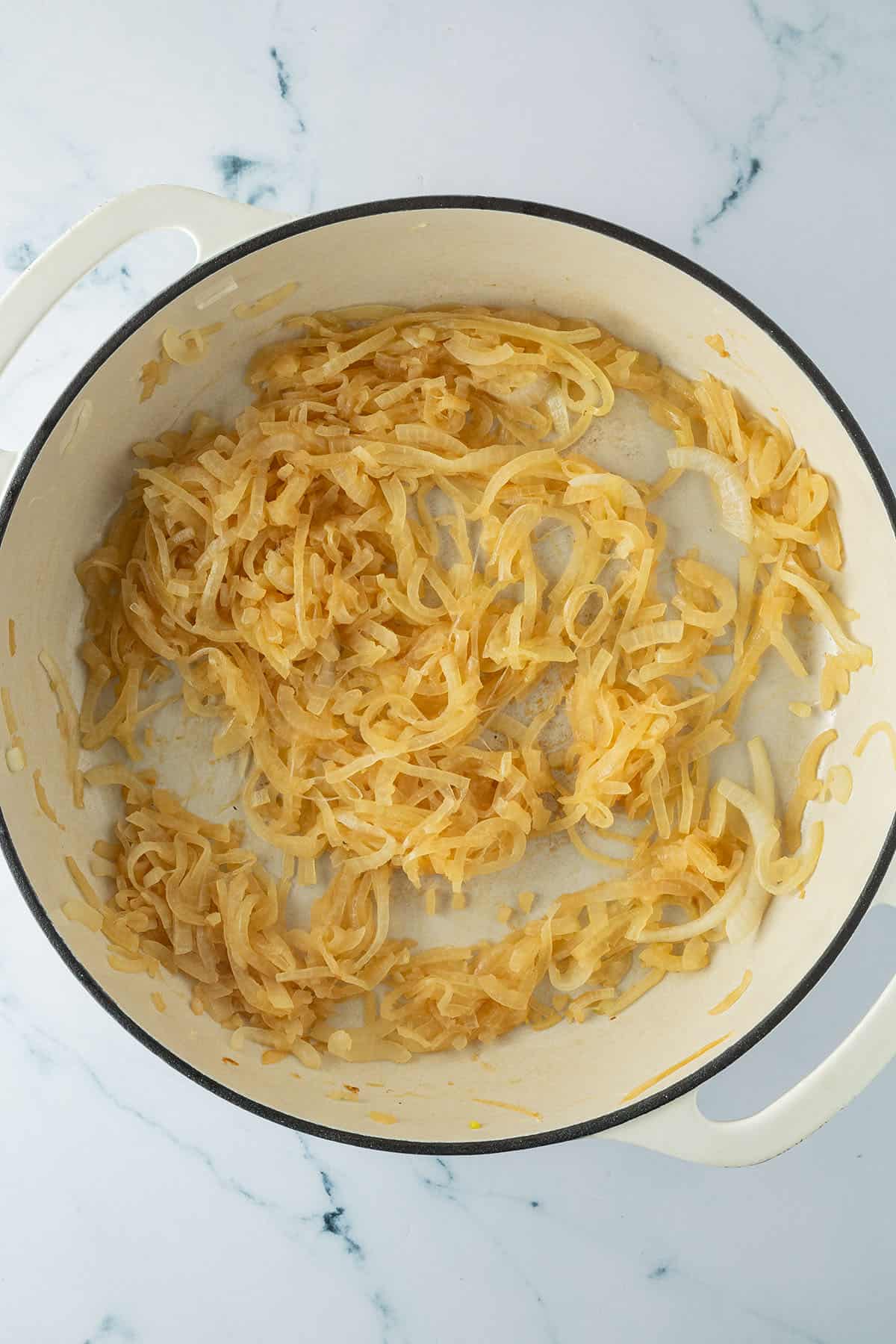 Weiche, lang angebratene karamellisierte Zwiebeln in einer großen Pfanne.