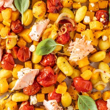 Nahaufnahme von einem One Blech Rezept mit Gnocchi, K&uuml;rbis, Feta Tomaten und Lachs.