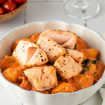 Cremige Gnocchi mit Lachs in tomatiger Marry Me Sahnesauce, angerichtet in einer wei&szlig;en Sch&uuml;ssel auf hellem Untergrund.