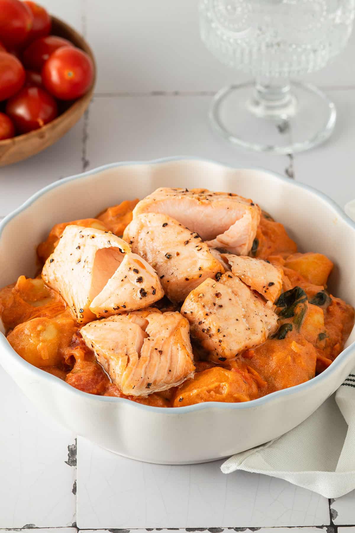 Cremige Gnocchi mit Lachs in tomatiger Marry Me Sahnesauce, angerichtet in einer wei&szlig;en Sch&uuml;ssel auf hellem Untergrund.