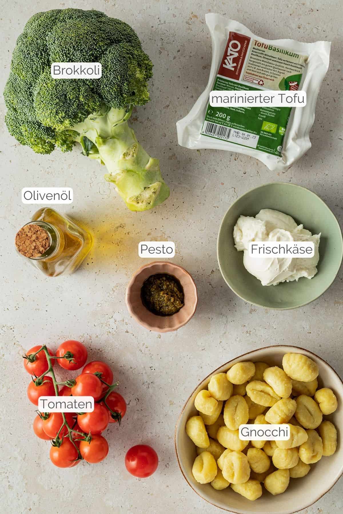 Alle Zutaten mit Textbeschriftungen, die für die Gnocchi Pesto Pfanne mit Gemüse benötigt werden.