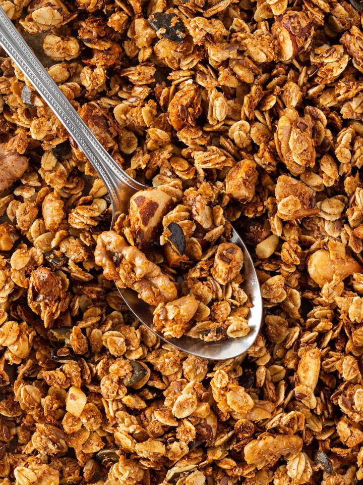 Nahaufnahme von einem knusprigen Granola mit einem silbernen L&ouml;ffel darin.
