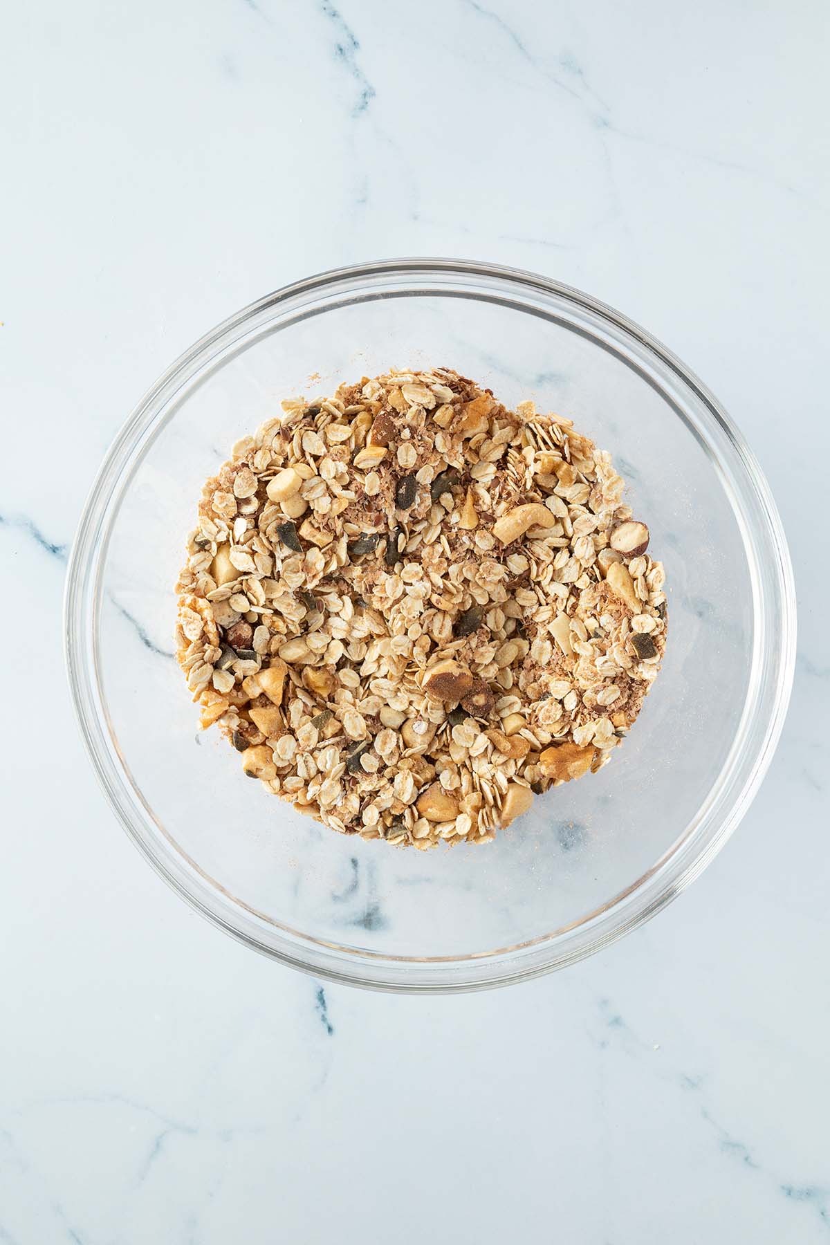 Trockene Granola-Zutaten in einer gro&szlig;en Glassch&uuml;ssel vermischt.