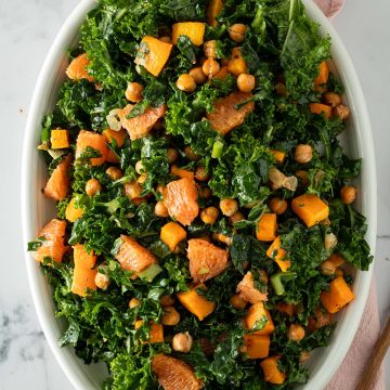 Winterlicher Gr&uuml;nkohlssalat mit Orange, K&uuml;rbis und Kichererbsen auf einem ovalen Teller.
