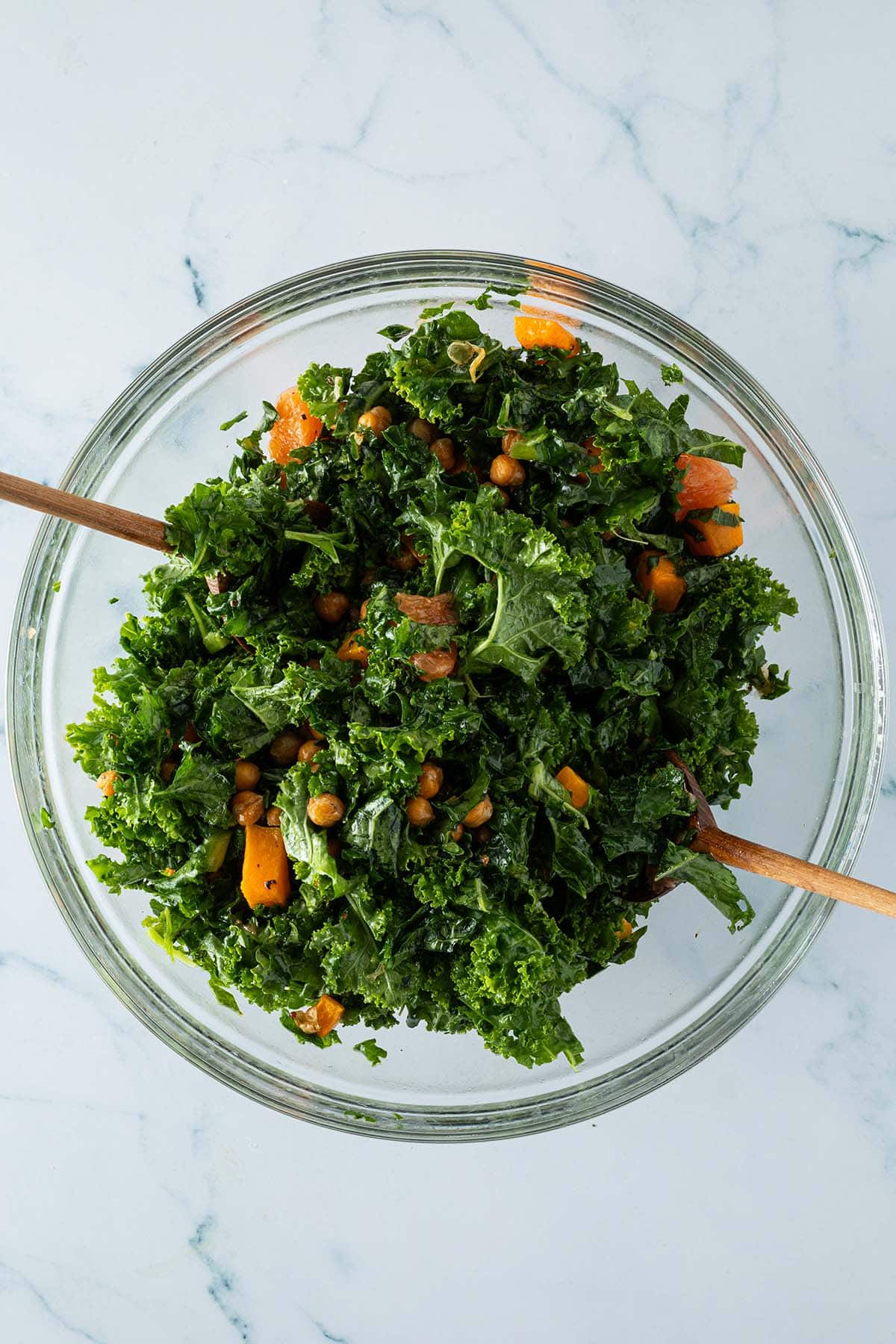 Gr&uuml;nkohlsalat wird in einer gro&szlig;en Sch&uuml;ssel mit Salatbesteck vermischt.