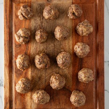 Im Ofen gebackene Hackb&auml;llchen auf einem Holzbrett.