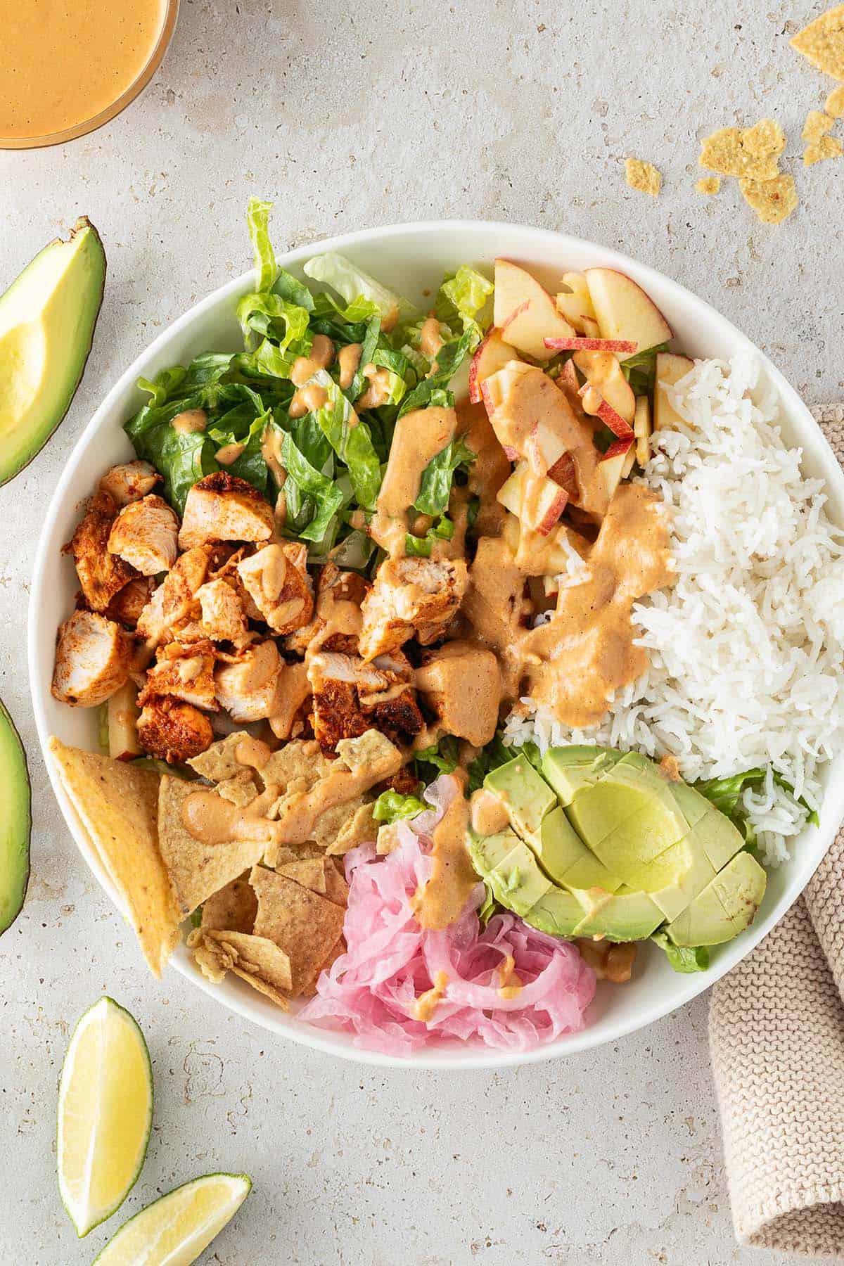 H&auml;hnchen Bowl mit Reis, Salat, Avocado, Zwiebeln, Nackos und cremigen Dressing, Deko im Bildrand.
