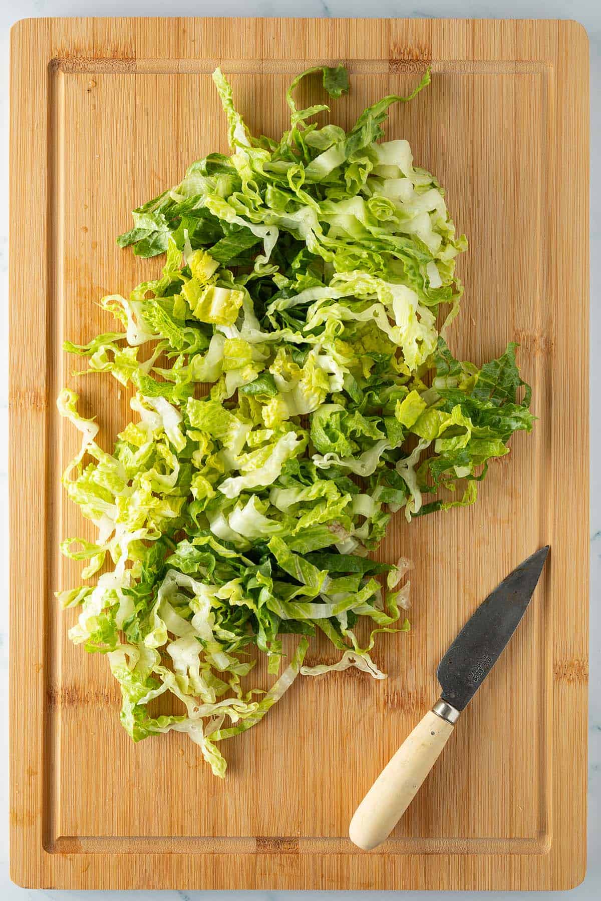 In d&uuml;nne Streifen geschnittener Salat auf einem Brett.