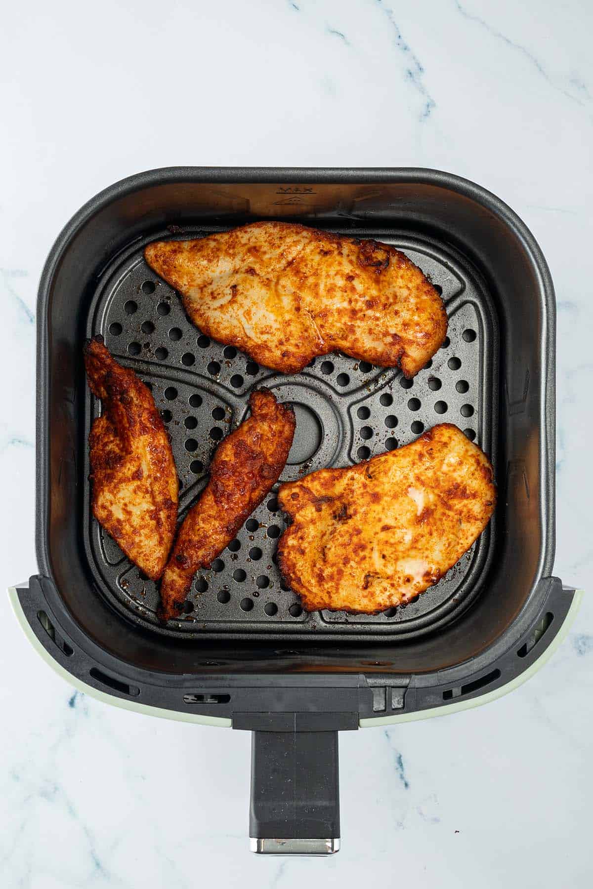 Knusprig gebackene H&auml;hnchenfilets in einem Hei&szlig;luftfritteusen-Korb.
