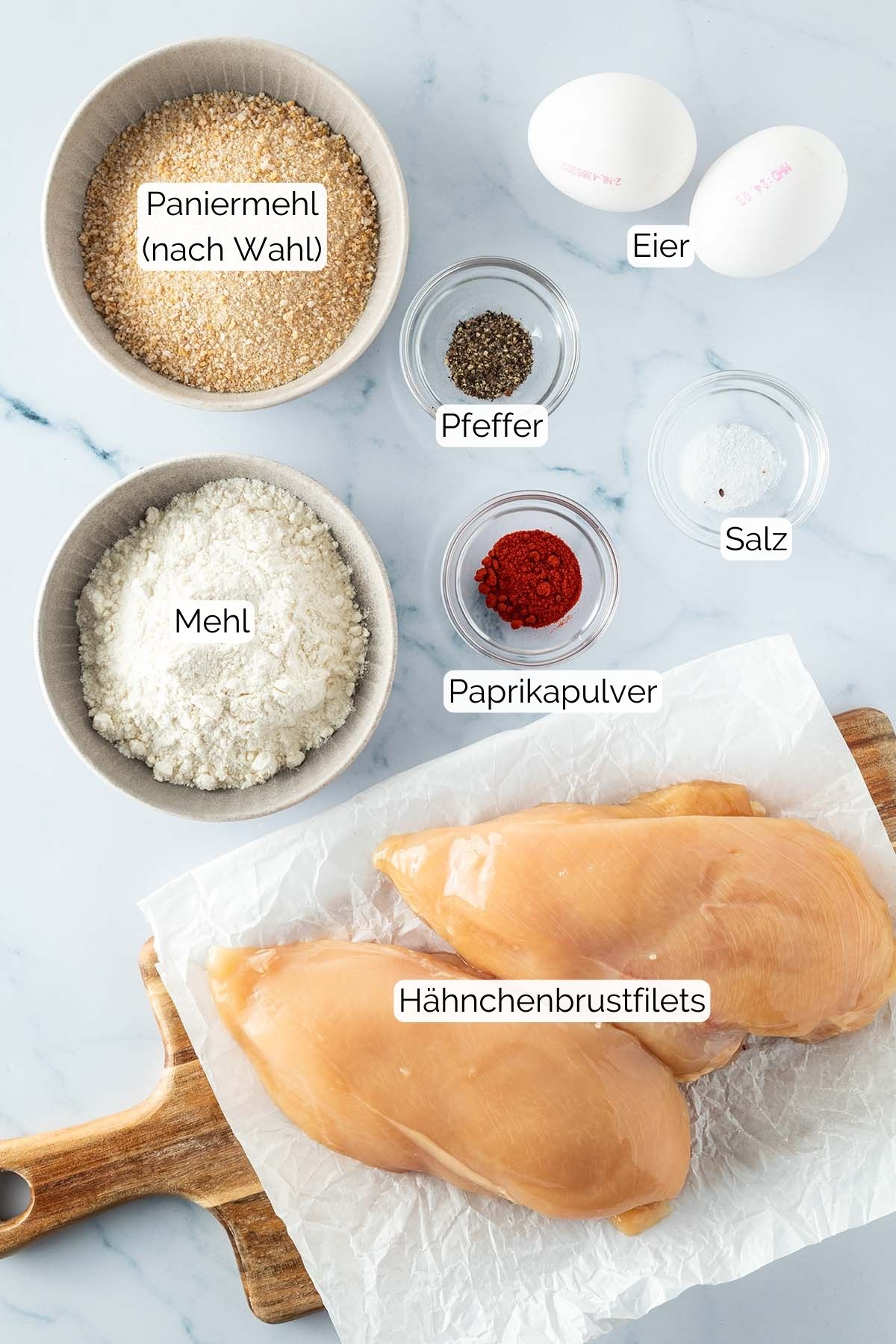 Foto aller Zutaten mit jeweiligen Textbeschriftungen, die f&uuml;r H&auml;hnchenschnitzel aus dem Backofen ben&ouml;tigt werden.