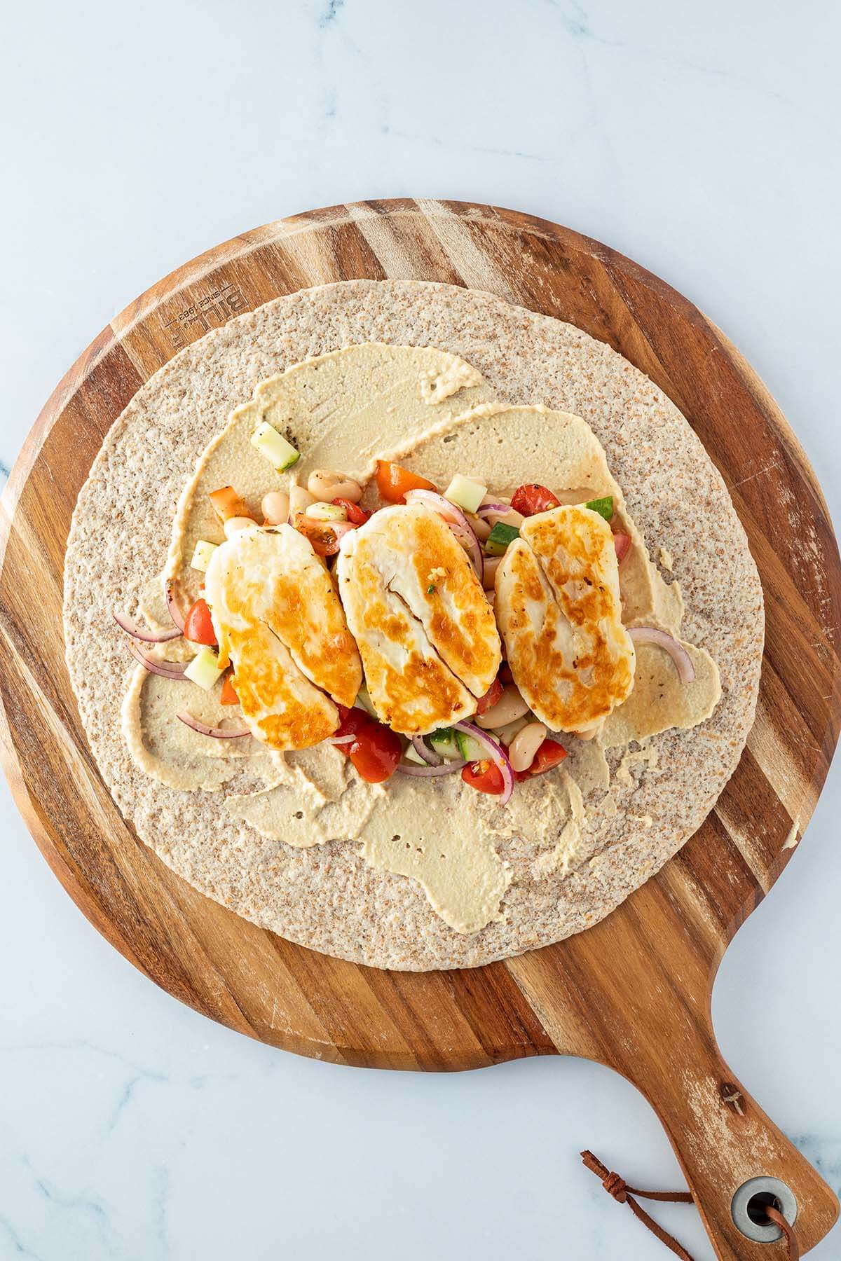 Offener Halloumi-Wrap auf einem Holzbrett.