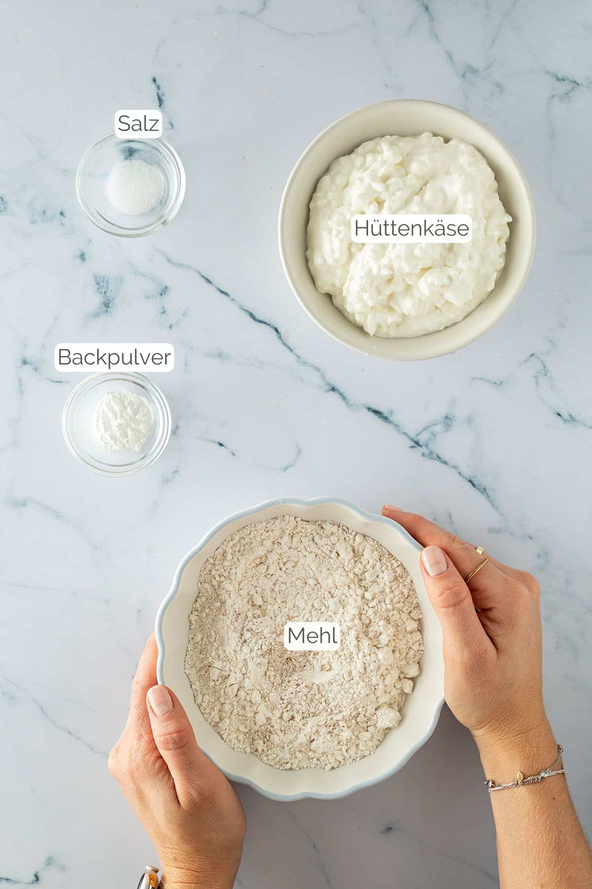 Alle Zutaten mit Textbeschriftungen, die du f&uuml;r den High Protein Pizzateig mit H&uuml;ttenk&auml;se ben&ouml;tigst.