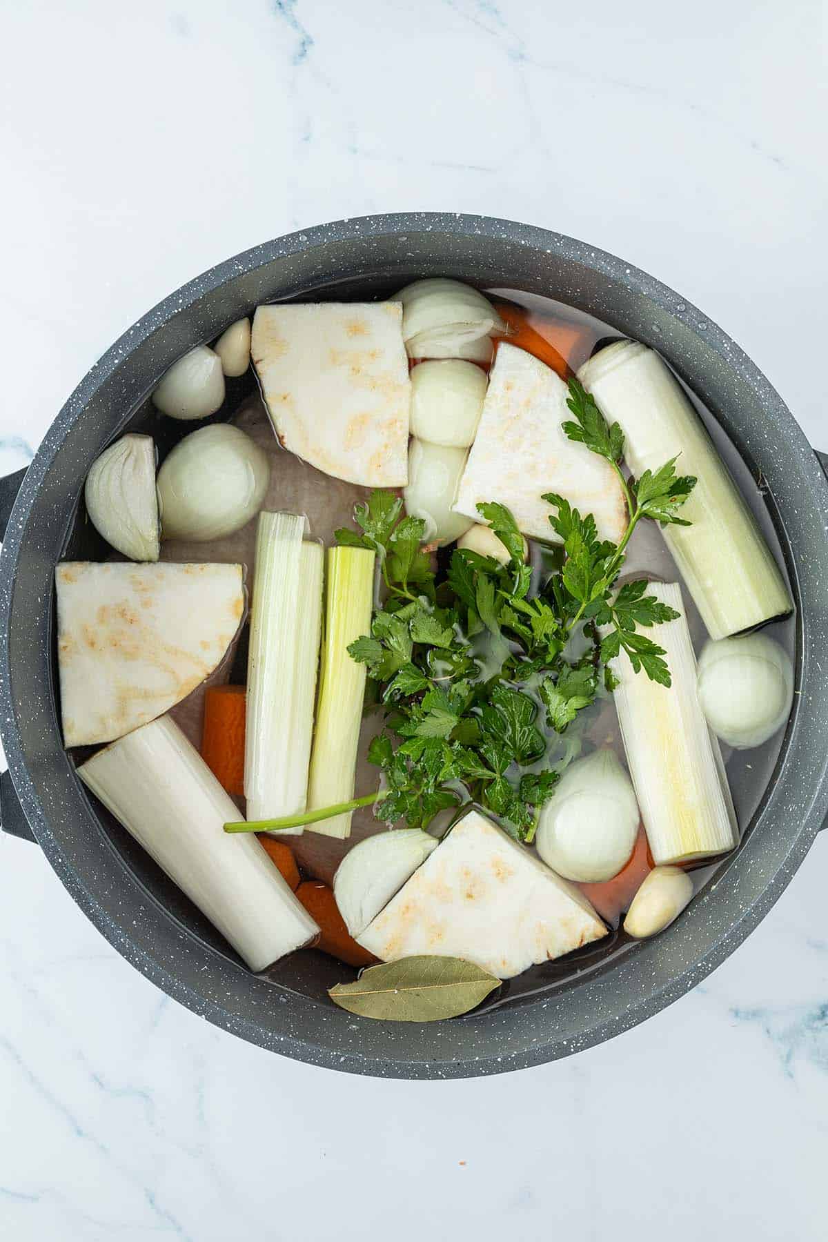 Ein Topf mit H&auml;hnchenschenkel, Suppengem&uuml;se und Wasser.