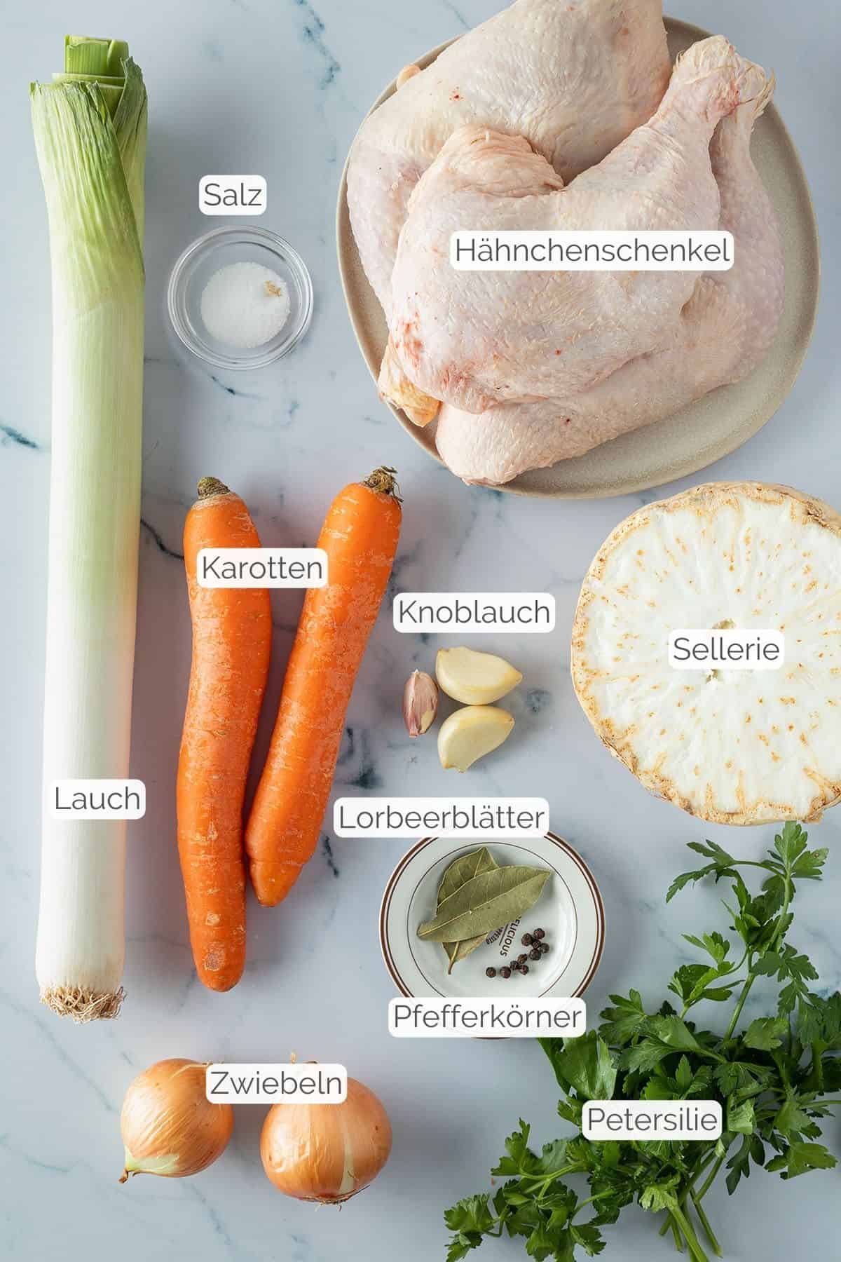 Alle Zutaten mit jeweiligen Textbeschriftungen, die f&uuml;r eine H&uuml;hnersuppe mit H&auml;hnchenschenkeln ben&ouml;tigt werden.