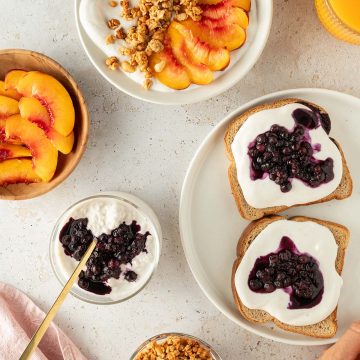 Verschiedene Fr&uuml;hst&uuml;cks-Gerichte mit der s&uuml;&szlig;en H&uuml;ttenk&auml;se-Creme auf einem hellen Untergrund.