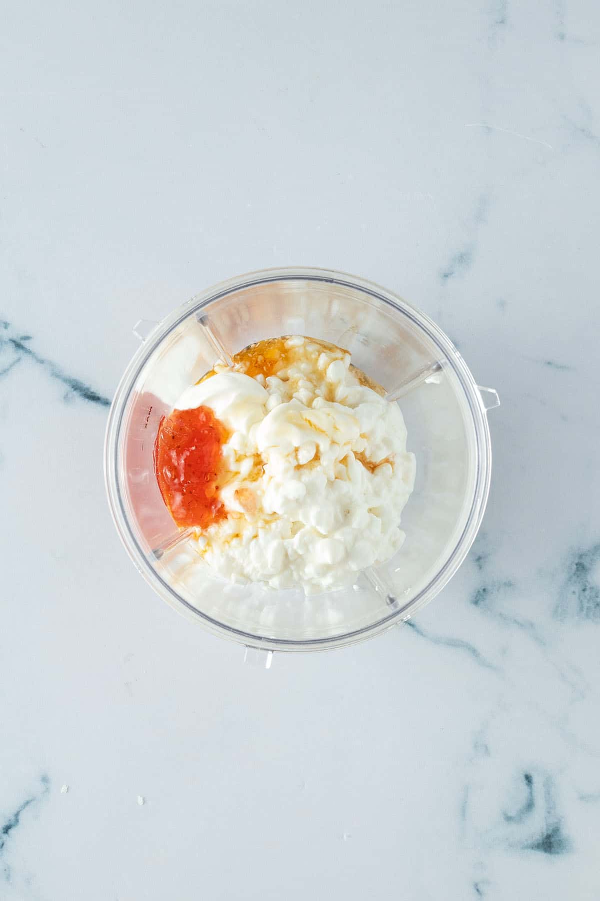 H&uuml;ttenk&auml;se, Schmand, Marmelade und Honig in einem Becher.