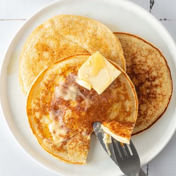 Drei H&uuml;ttenk&auml;se Pancakes auf einem Teller, auf wei&szlig;en Flie&szlig;en.