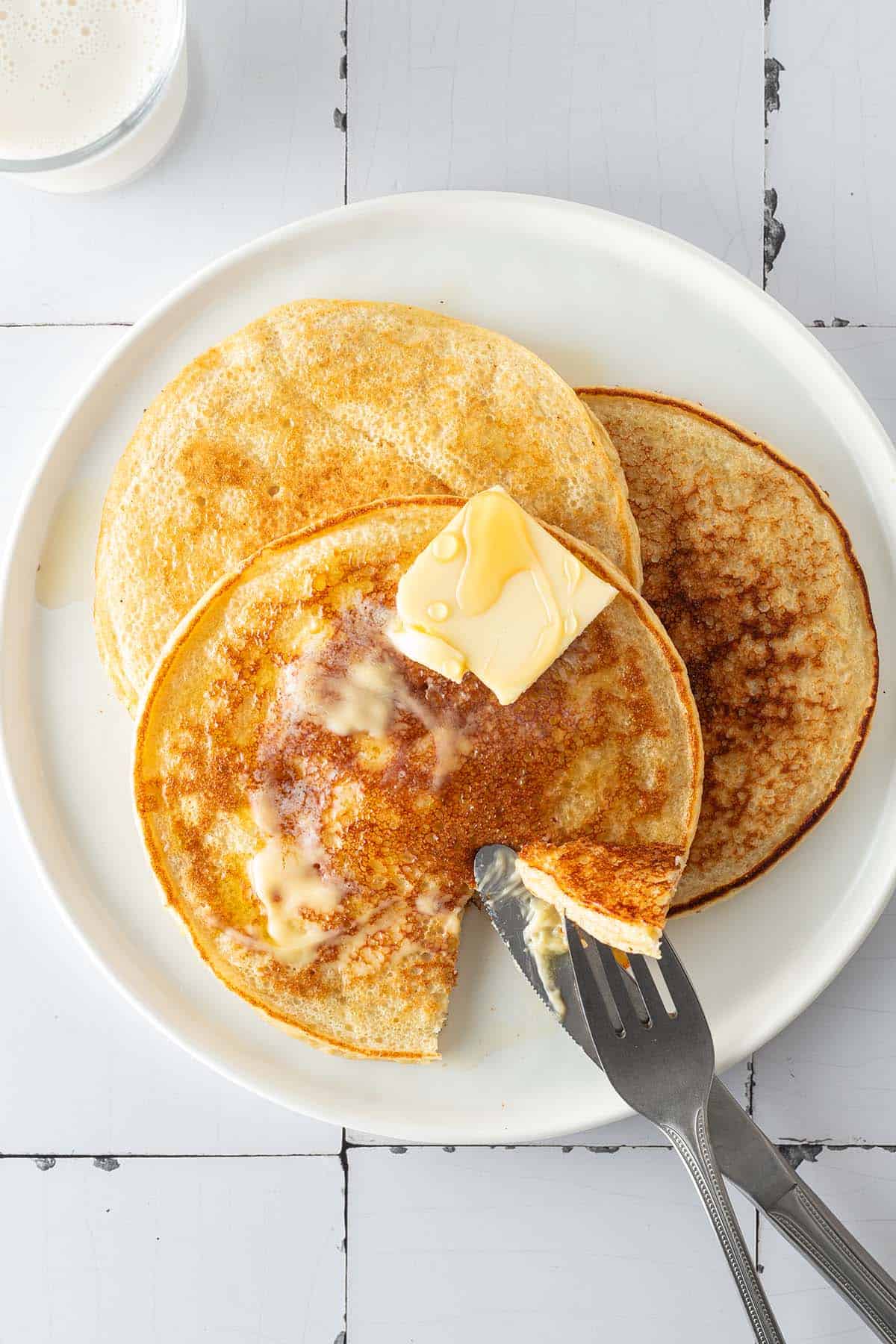 Drei H&uuml;ttenk&auml;se Pancakes auf einem Teller, auf wei&szlig;en Flie&szlig;en.