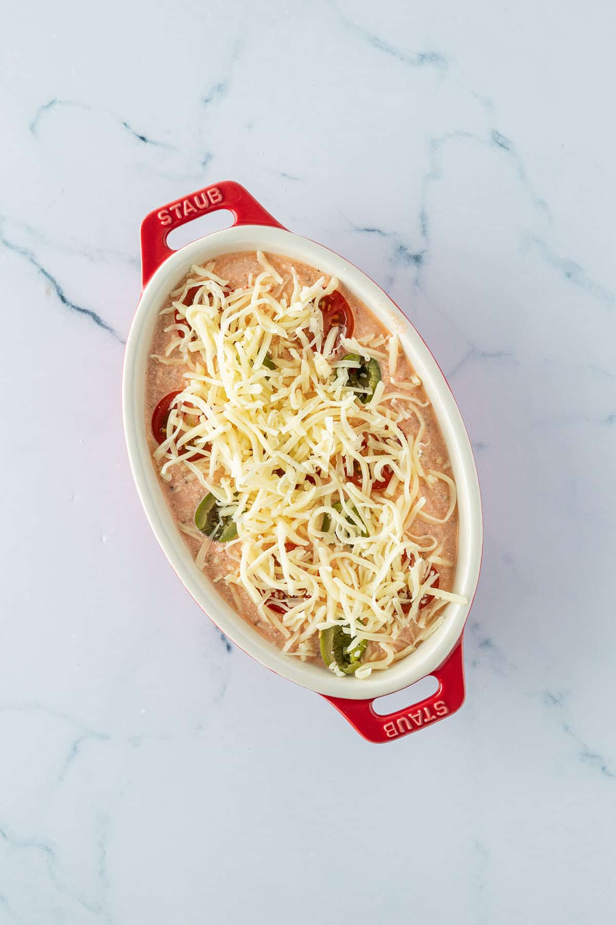 H&uuml;ttenk&auml;se Dips mit Toppings und geriebenem K&auml;se in einer kleinen, ovalen Auflaufform.