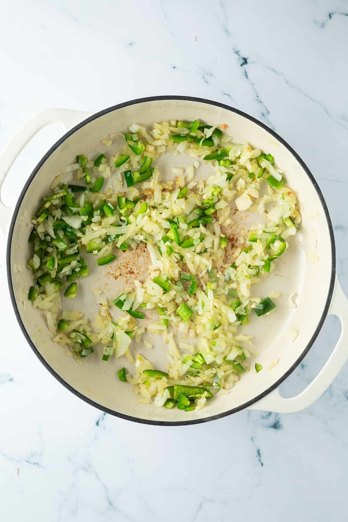 Zwiebeln, Knoblauch und Jalape&ntilde;o werden in einer gro&szlig;en Pfanne angebraten.