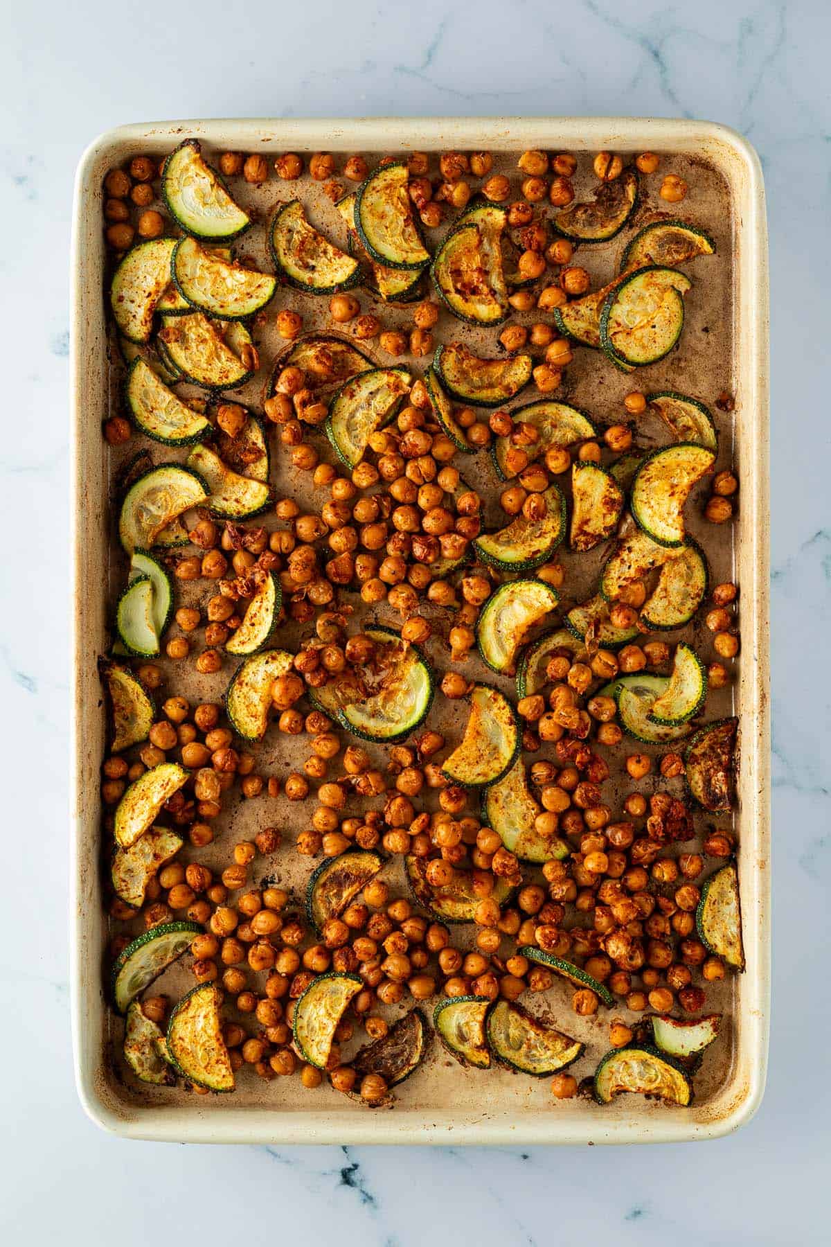Im Ofen ger&ouml;stete Zucchini-Scheiben und Kichererbsen auf einem Blech.