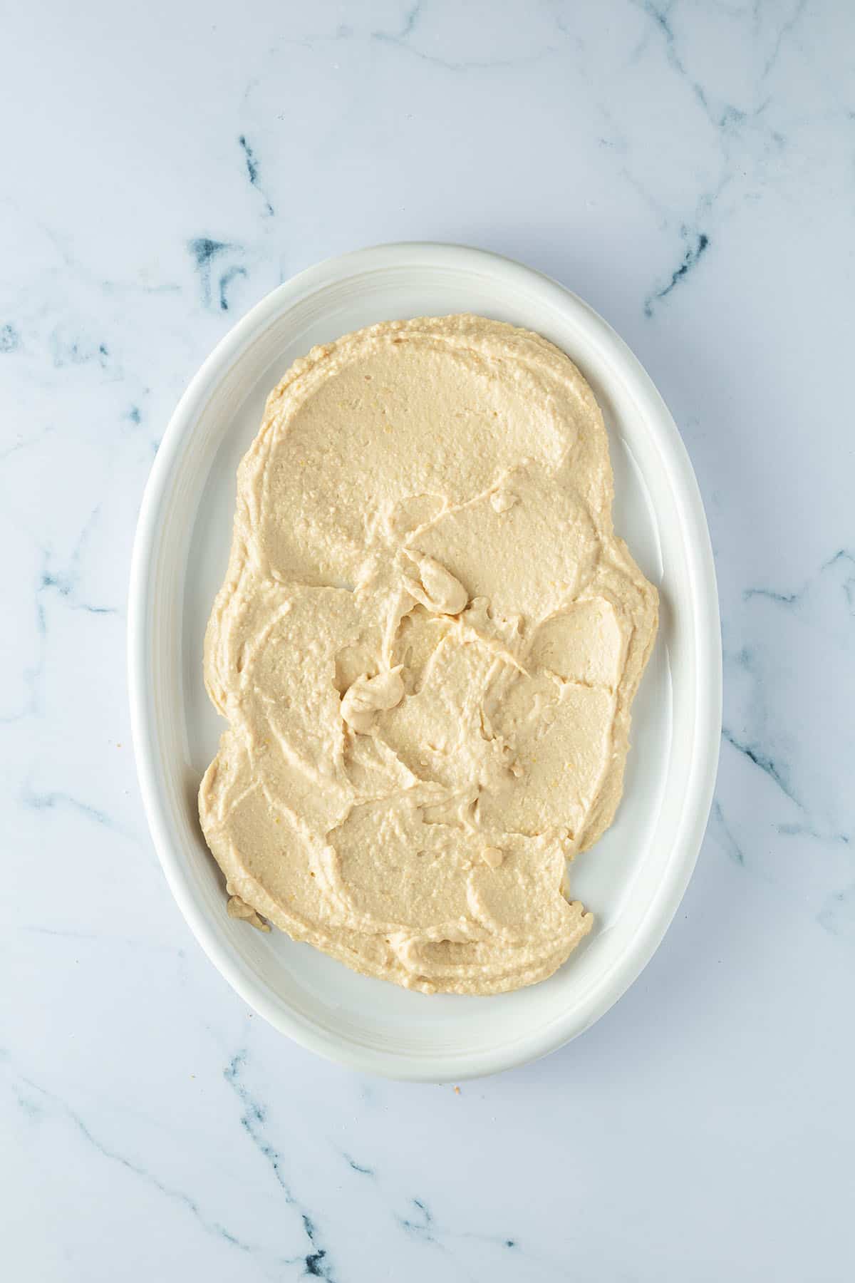 Hummus Dip auf einem l&auml;nglichen Teller verteilt.