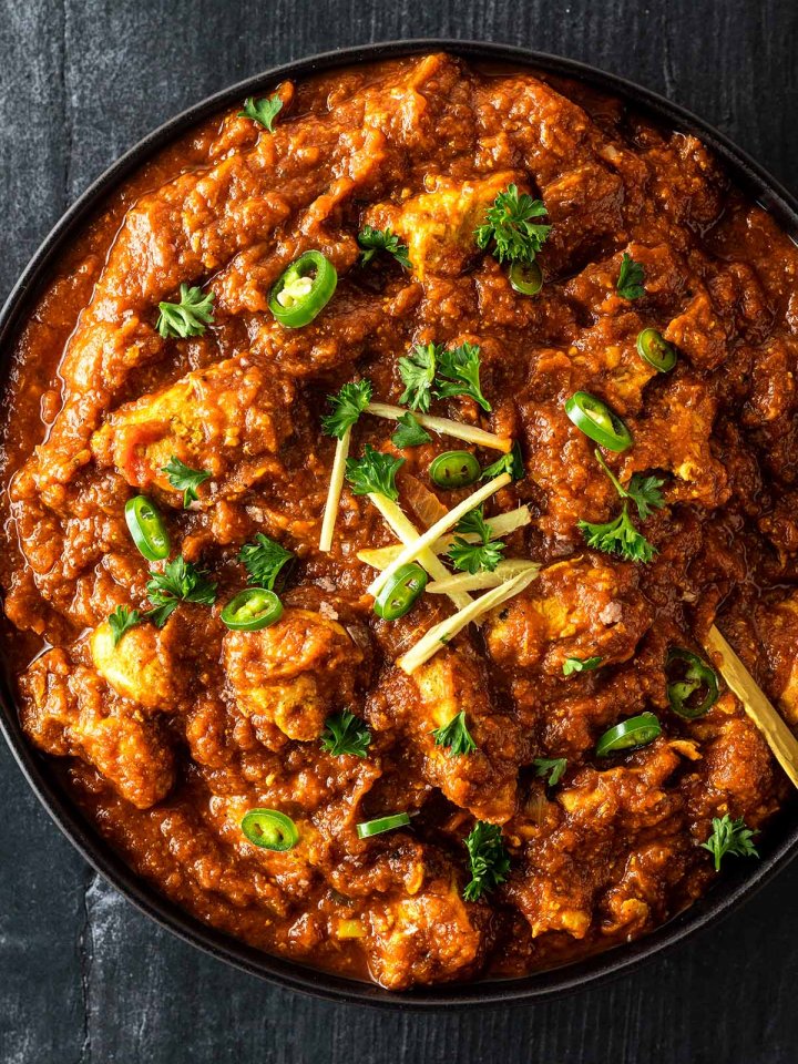 Indisches H&auml;hnchen Curry mit einer cremigen Tomatensauce serviert mit Chilis, Ingwer und Kr&auml;utern.