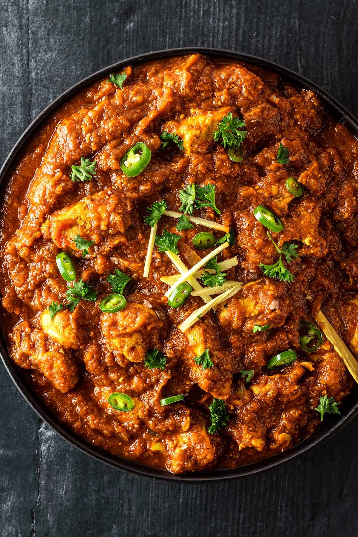 Indisches H&auml;hnchen Curry mit einer cremigen Tomatensauce serviert mit Chilis, Ingwer und Kr&auml;utern.