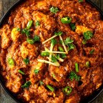 Foto von einer gro&szlig;en Sch&uuml;ssel mit einem indischen H&auml;hnchen Tikka Masala auf einem dunklen Holzuntergrund.