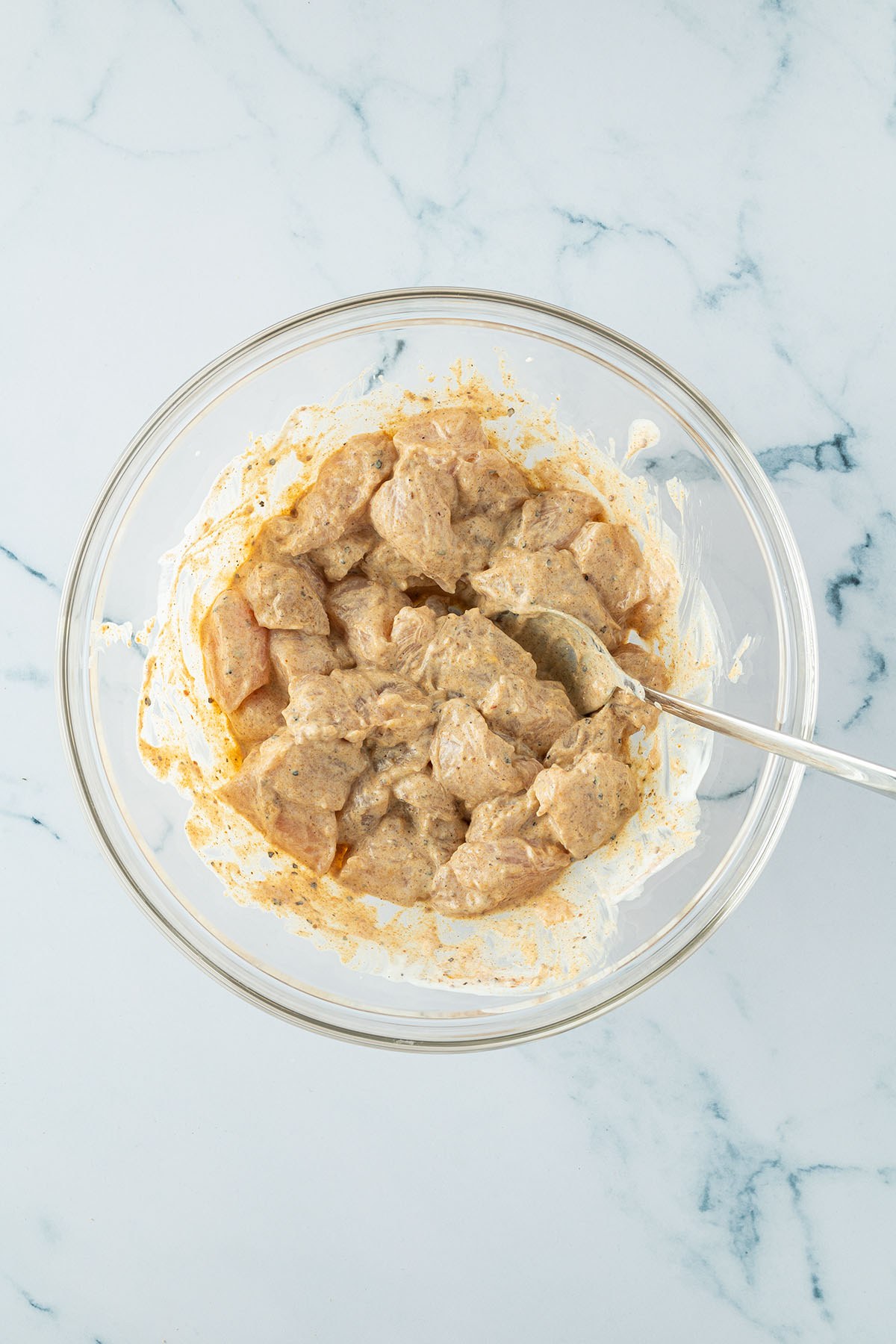 Glassch&uuml;ssel mit rohem, in St&uuml;cke geschnittenen und einer Joghurt-Marinade eingelegten H&auml;hnchenfleisch.